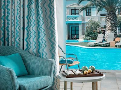 Pohodlné křeslo s polštářem vedle bazénu a stůl s jablky a vodou v hotelu.