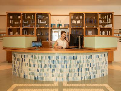 Hotelreceptie met een halfcirkelvormige balie en een medewerker achter de computer.