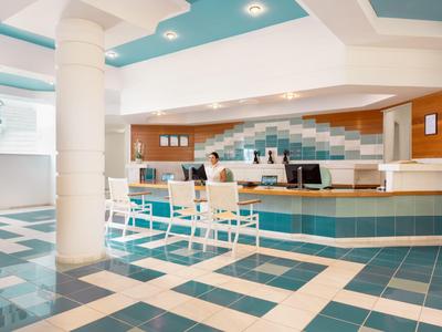 Lichte hotel lobby met receptie, stoelen en moderne blauwe en witte tegels.