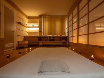 Een rustige massageruimte met warm licht en kaarsen voor een ontspannen sfeer.