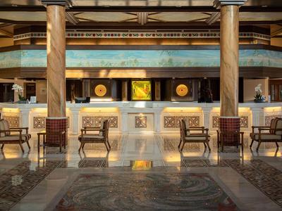 Moderne Hotellobby mit Rezeption, Stühlen und warmem Licht.