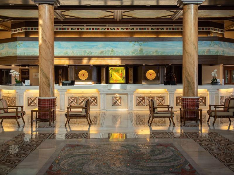 Stylové hotelové lobby s mramorovou recepcí a dřevěnými židlemi na lesklé podlaze.