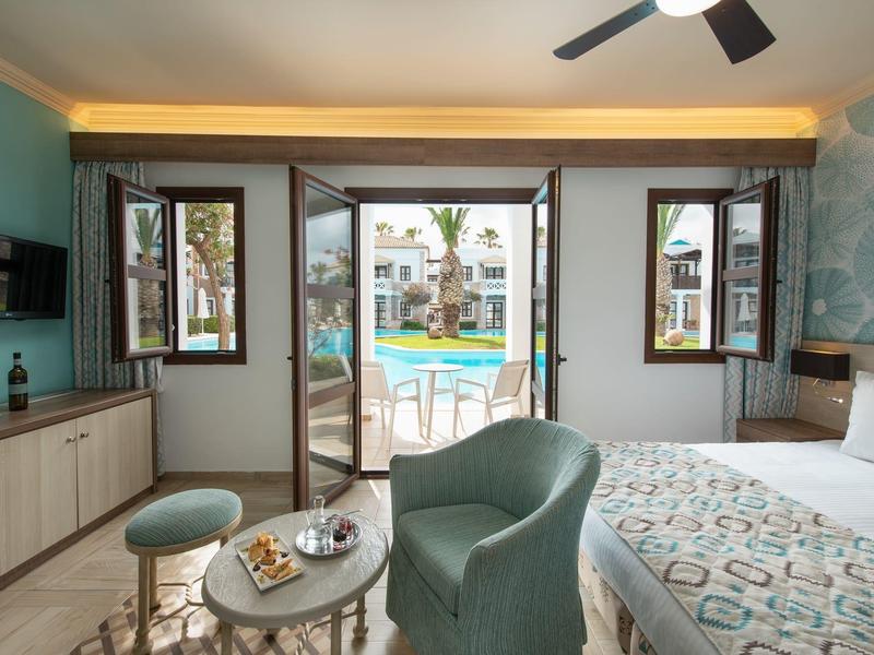 Moderní hotelový pokoj s výhledem na bazén a přilehlé budovy.