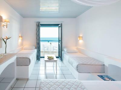 Helles, schlichtes Zimmer mit zwei Einzelbetten, kleinem Tisch und offenem Fenster zum Meer.