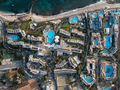 Nadmorski kurort z wieloma dużymi budynkami hotelowymi i niebieskimi basenami blisko morza.