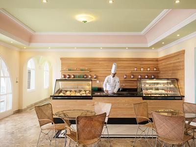 Moderne Bäckerei mit Tresen, Theken und Bäcker in weißer Uniform hinter dem Verkaufstresen.