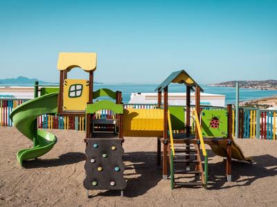 Bunter Kinderspielplatz mit Rutsche und Kletterelementen am Strand mit Meerblick.
