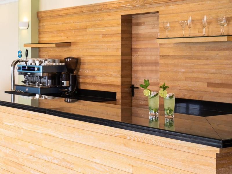Moderner Hotel-Barbereich mit Kaffeemaschine und Vase auf schwarzer Arbeitsplatte aus Holz