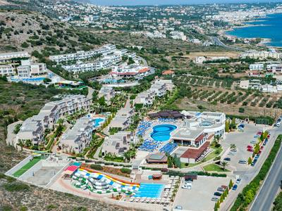 Luftaufnahme eines Hotels mit Pool, Sonnenliegen und Blick auf das Meer und umliegende Landschaft.