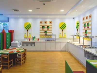 Bunte Kinderspielecke mit Tischen, Stühlen, Wanddekorationen und vielen Spielzeugen.