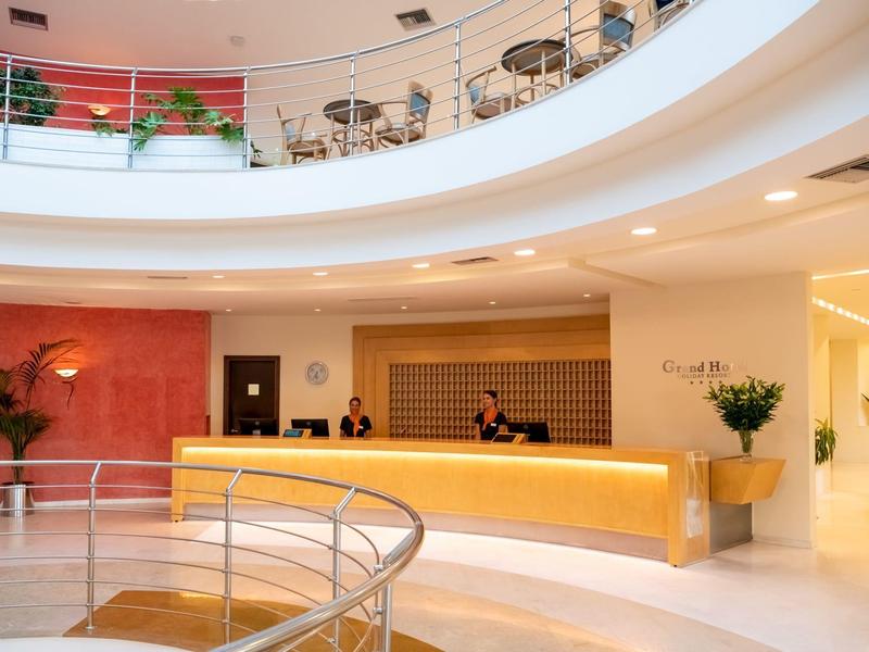 Recepción de hotel moderna y luminosa con mostrador curvo y barandilla redonda.