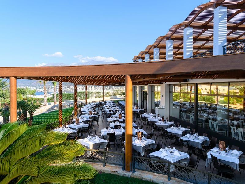 Restaurante elegante de hotel con terraza cubierta, mesas preparadas y vista al jardín.