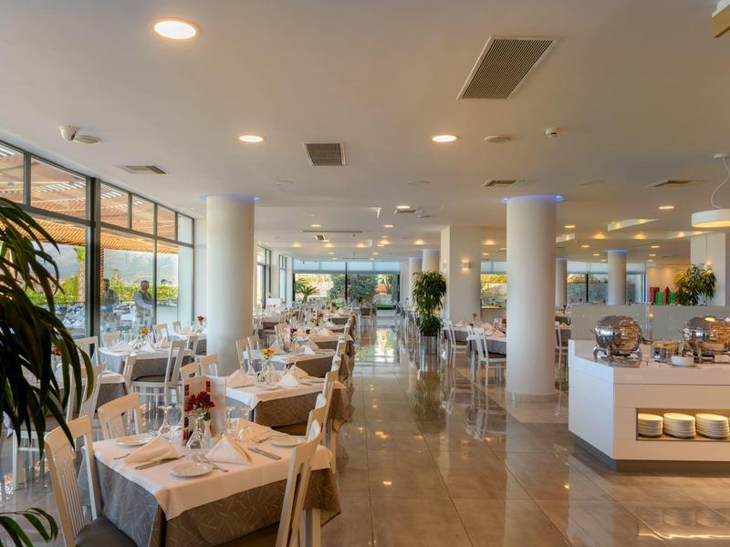 Área de restaurante de hotel moderna y luminosa con mesas elegantemente preparadas y grandes ventanas.
