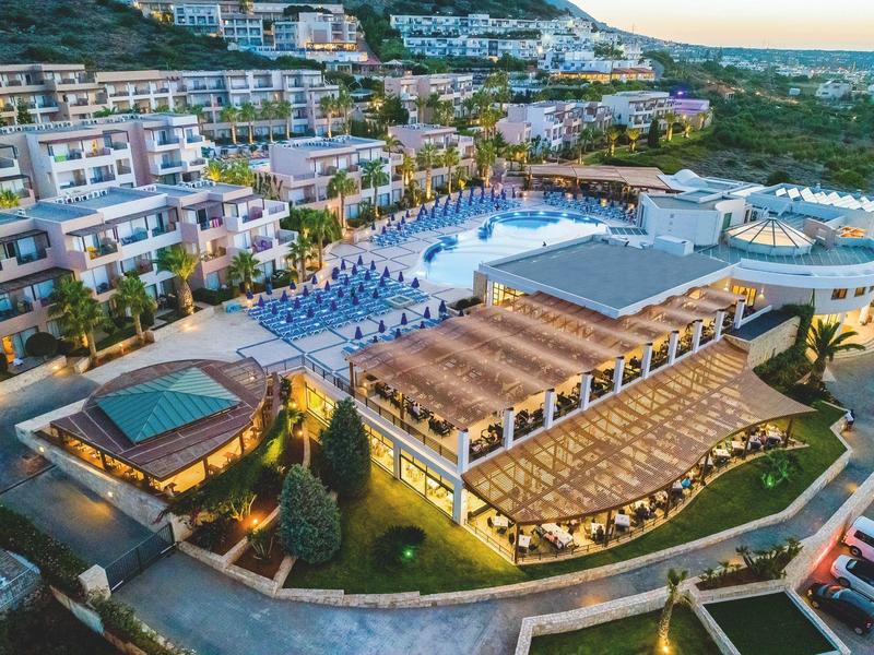 Vista aérea de un gran complejo hotelero con piscinas, tumbonas y edificios alrededor en la ladera.