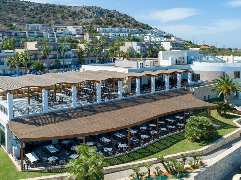 Resort de lujo con piscina, tumbonas y arquitectura blanca en una pendiente con vista al mar.