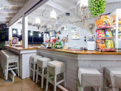 Světlý bar s bílými stoličkami, dřevěným pultem a občerstvením v moderním námořním prostředí.