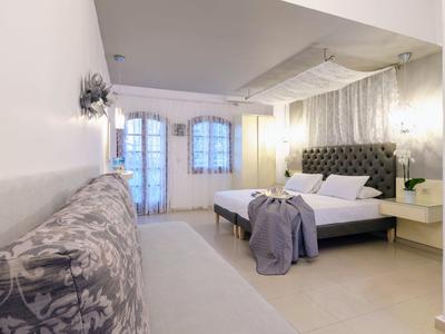 Moderní ložnice s čalouněnou postelí, lavičkou, velkými okny a světlými stěnami.