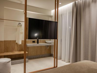 Habitación de hotel moderna con televisor grande, detalles de madera y luz tenue.