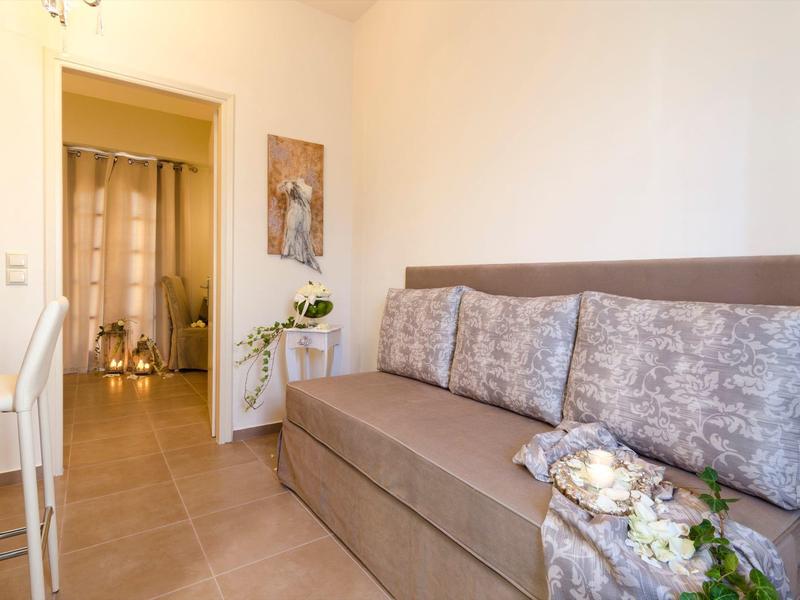 Moderní obývací pokoj se šedou pohovkou, polštáři a dekoracemi v světlém prostoru.