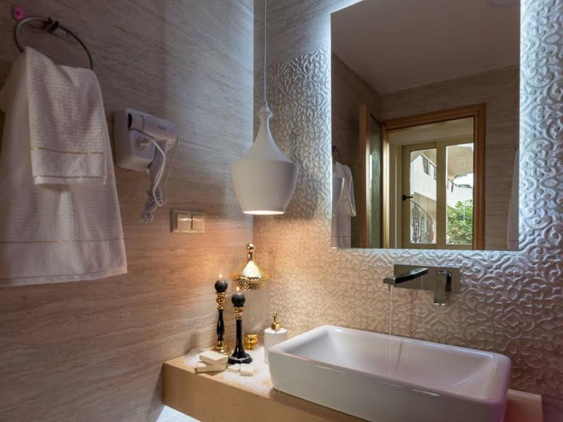 Moderní koupelna s texturovanou zdí, velkým zrcadlem a obdélníkovým umyvadlem.