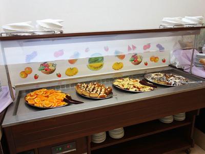 Buffet mit vier Tabletts voller Snacks und buntem Fischdekor an der Rückwand.