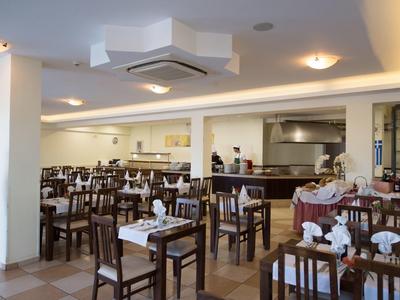 Großer heller Speisesaal mit vielen Holztischen, Stühlen und gedeckten Plätzen.