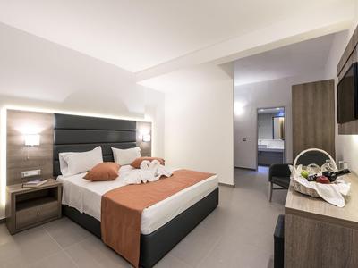 Helles Hotelzimmer mit Doppelbett, Nachtlampen, Holzmöbeln und Fruchtkorb auf Kommode.