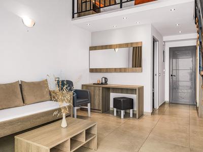Helles Wohnzimmer mit braunem Sofa, Holzregal, großem Spiegel und heller Fliesenboden.