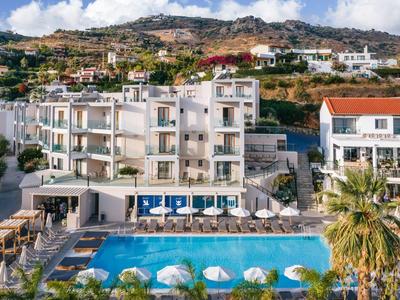 Hotel s bazénem, slunečníky a lehátky před kopci pod modrou oblohou