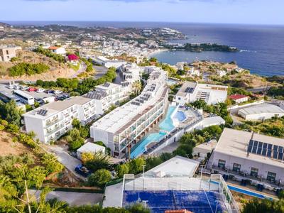 Letecký snímek resortu s několika budovami, bazény a výhledem na moře.