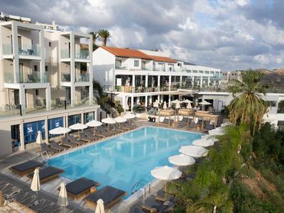 Hotel s bazénem na kopci s deštníky a lehátky pod oblačnou oblohou