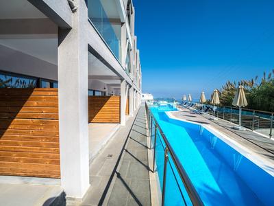 Moderní venkovní bazén u hotelu s lehátky a slunečnou oblohou.