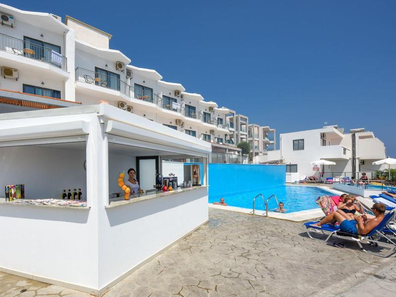 Moderní hotelový bazén s barem a lehátky pod modrou oblohou.