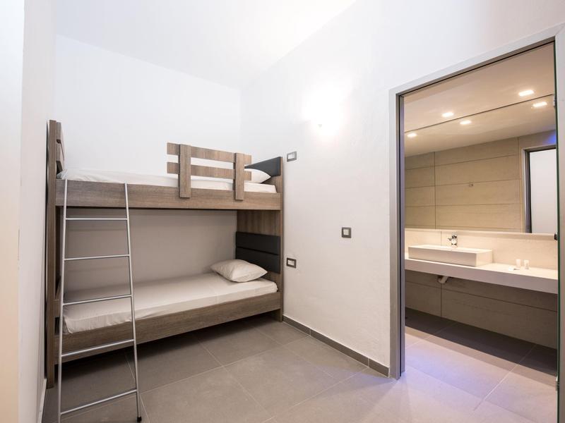 Jednoduše zařízený pokoj s palandou a přilehlou koupelnou se sprchou.