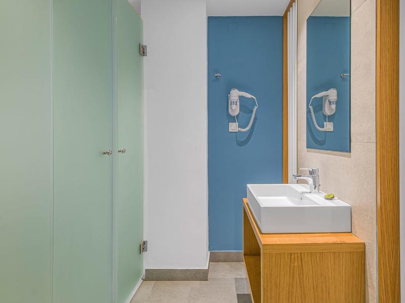 Moderní koupelna s umyvadlem na dřevěné skříňce a modrou stěnou s fénem.