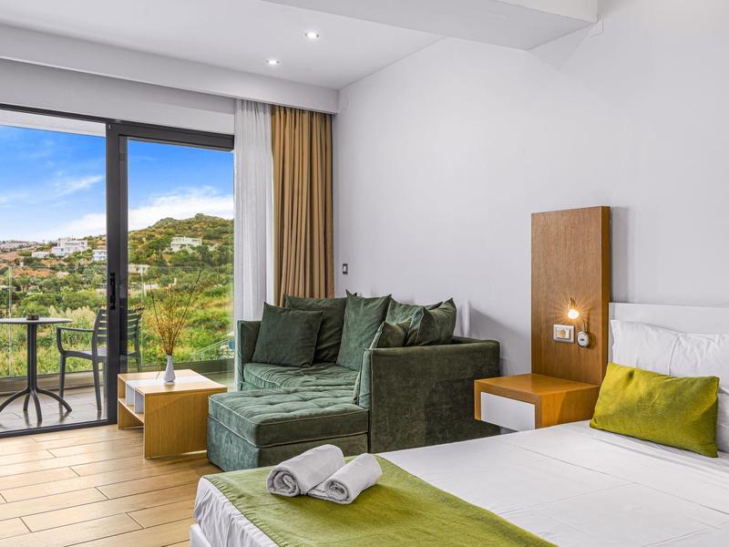 Moderní hotelový pokoj s postelí, pohovkou a balkonem s výhledem na hory.