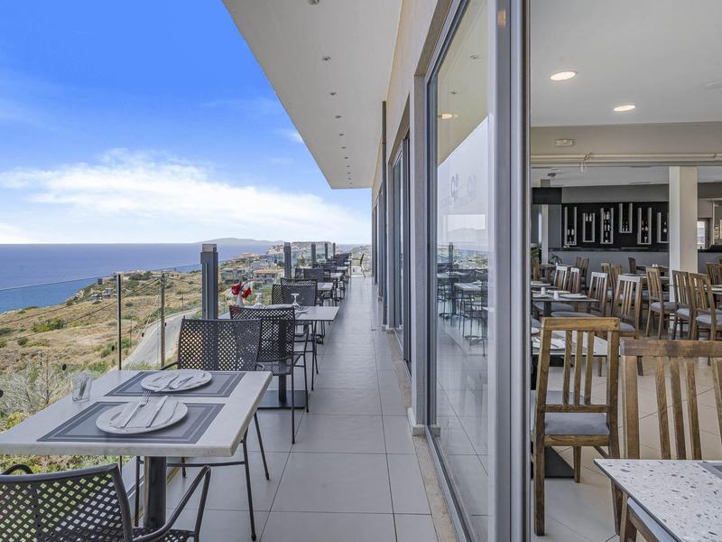 Stoly na balkóně s výhledem na moře a interiér restaurace za jasného počasí.