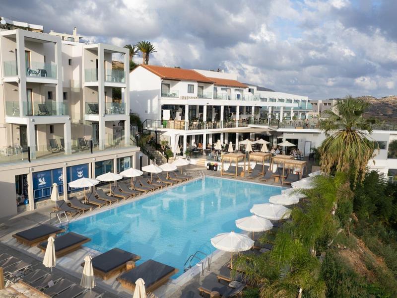 Hotel s bazénem na kopci s deštníky a lehátky pod oblačnou oblohou