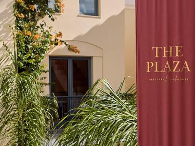 Balkon met planten voor een crèmekleurige gevel en rode gordijn met logo