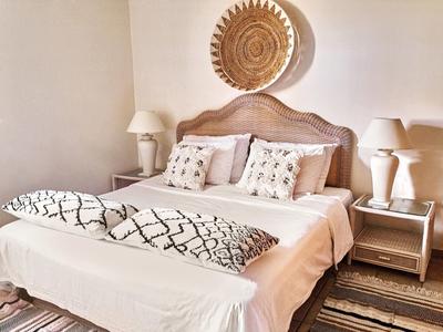 Modern eingerichtetes Schlafzimmer mit Doppelbett, Nachttischen und dekorativen Kissen.