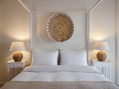 Schlichtes Hotelzimmer mit Doppelbett, weißen Kissen, zwei Nachttischen und runden Lampen.