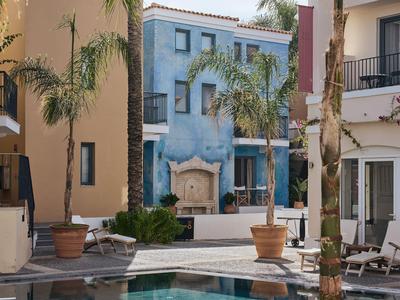 Binnenplaats met palmbomen en zitgedeelte tussen meerlaagse gebouwen in warme kleuren