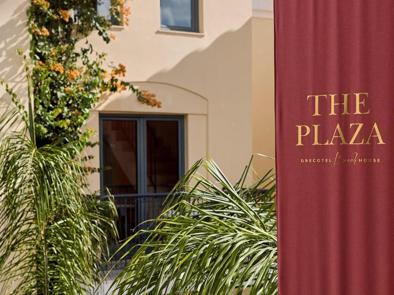 Blick auf eine Hotelwand mit Pflanzen und einem roten Vorhang mit goldenem Schriftzug