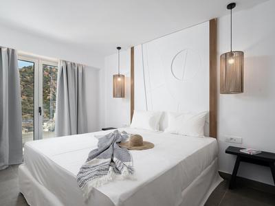 Moderne hotelkamer met groot bed, twee hanglampen en balkon met uitzicht.