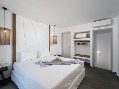 Minimalistische hotelkamer met tweepersoonsbed, modern design en open kledingkast.
