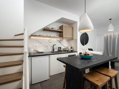 Moderne kleine keuken met houten aanrecht, krukken en trap in lichte ruimte