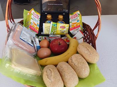 Een mand met ontbijtproducten zoals brood, bananen, eieren en jam.