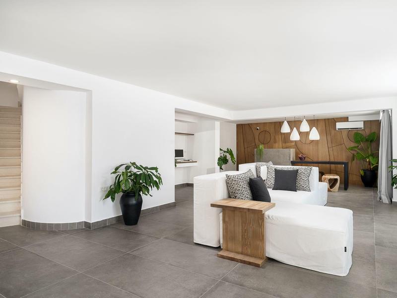 Moderne gezellige woonkamer met witte bank, houten tafel en ingebouwde planken in lichte ruimte.