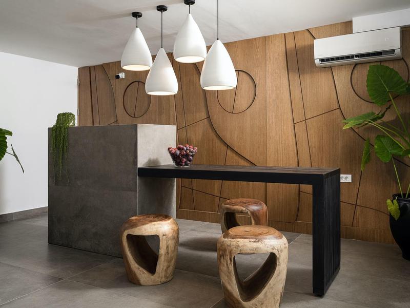 Moderne receptieruimte met houten wand, zwarte tafel en drie decoratieve krukken.