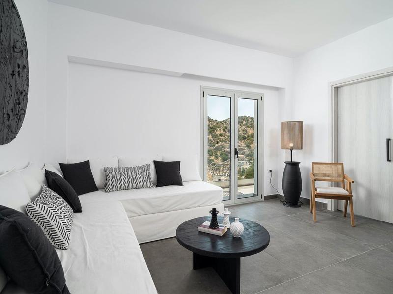 Lichte, minimalistische woonkamer met witte banken, zwarte tafel en groot raam met uitzicht op groen.